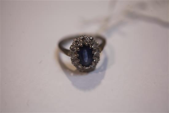 An 18ct white gold, sapphire and diamond oval cluster ring, size K.